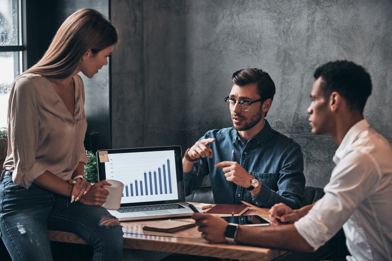Três gestores analisam os principais indicadores da contabilidade no laptop e traçam estratégias a partir desses dados.