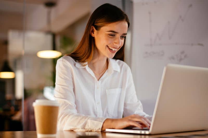 Mulher trabalhando em escritório analisa substituir planilha de precificação por sistema automatizado.