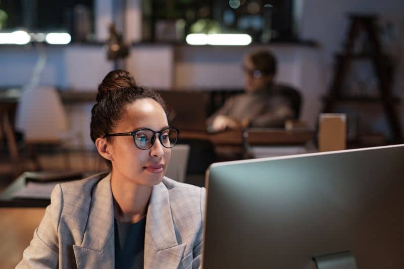 Mulher trabalhando em escritório analisa os indicadores financeiros de uma empresa no computador.