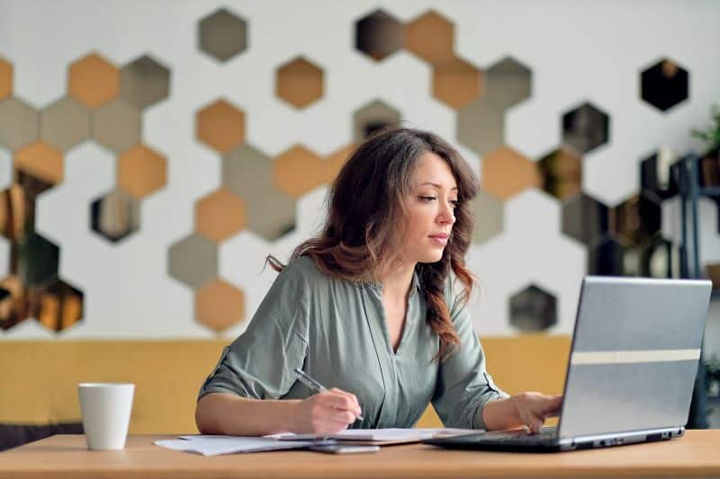 mulher em agência de marketing verificando relação de faturamento no computador