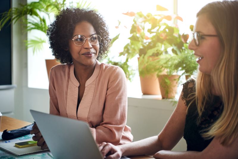 O que é saas​: duas mulheres trabalhando e conversando em escritório.