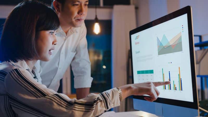 Tipos de gráficos estatísticos​: mulher e homem analisando gráficos no computador
