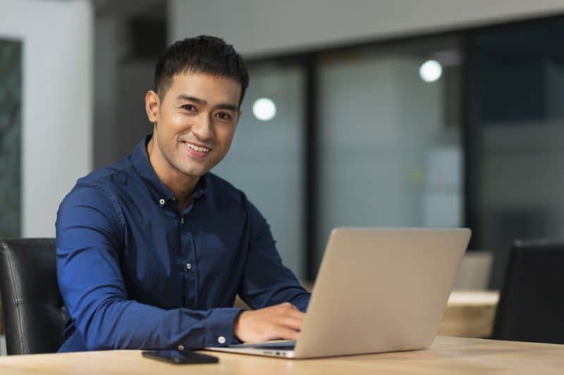 Índice de desempenho​: homem sorridente trabalhando no computador.