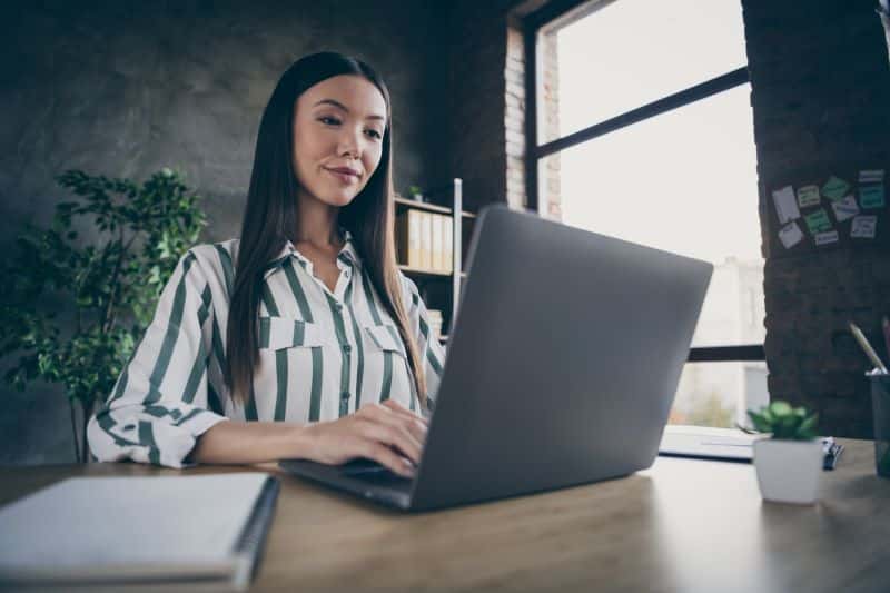 antecipação de recebíveis​: mulher com sorriso leve trabalhando em escritório
