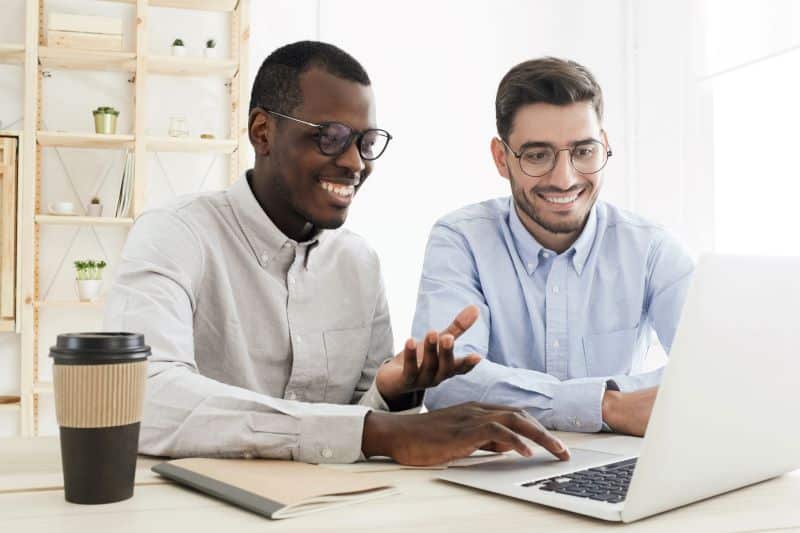 plataforma low code​: dois homens sorridentes trabalhando em computador no escritório