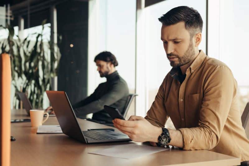 mensagem de lembrete de pagamento para cliente: homem no escritório recebendo notificação no celular
