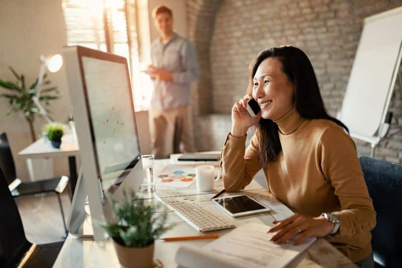 calculadora de ROI: mulher trabalhando no escritório falando com cliente em ligação por celular